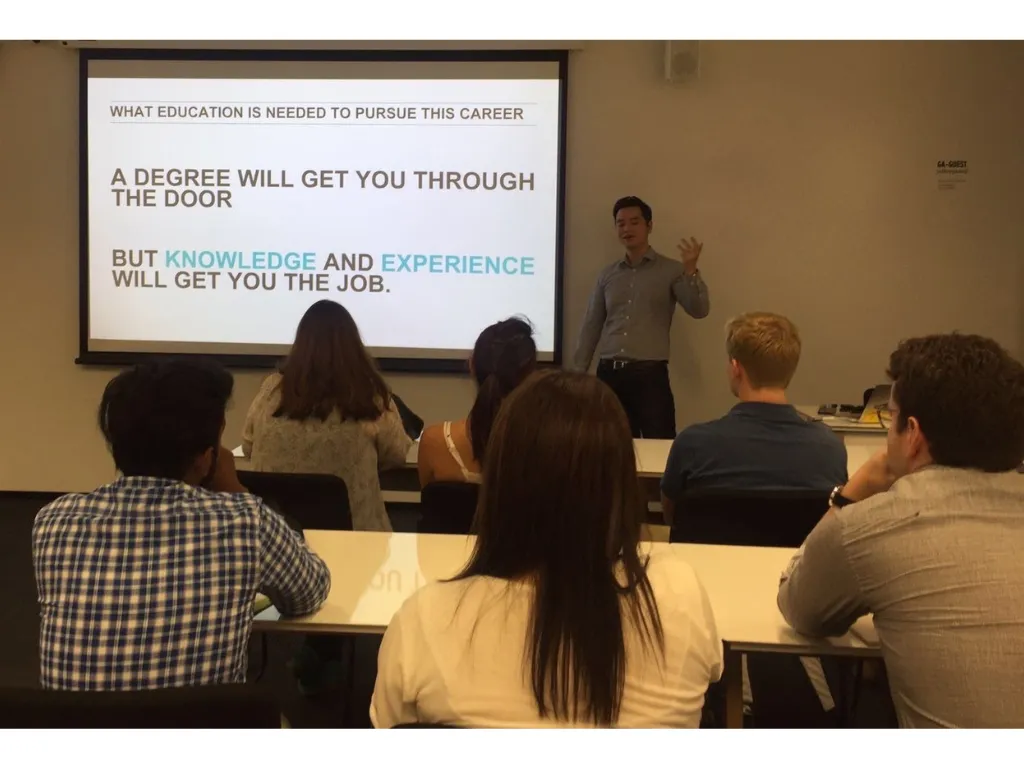 Dave teaching a room of students, with a slide about knowledge and experience behind him.